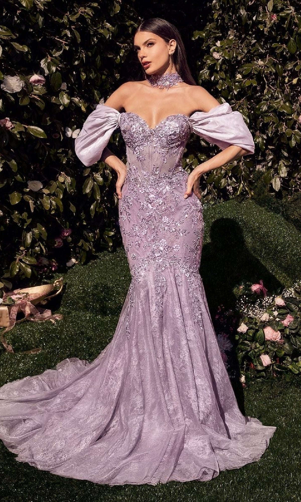 A woman stands outdoors in the Andrea & Leo A1354 Long Mermaid Prom Dress, a strapless, form-fitting lavender gown with beaded floral embroidery, lace details, matching off-the-shoulder sleeves, and a choker.